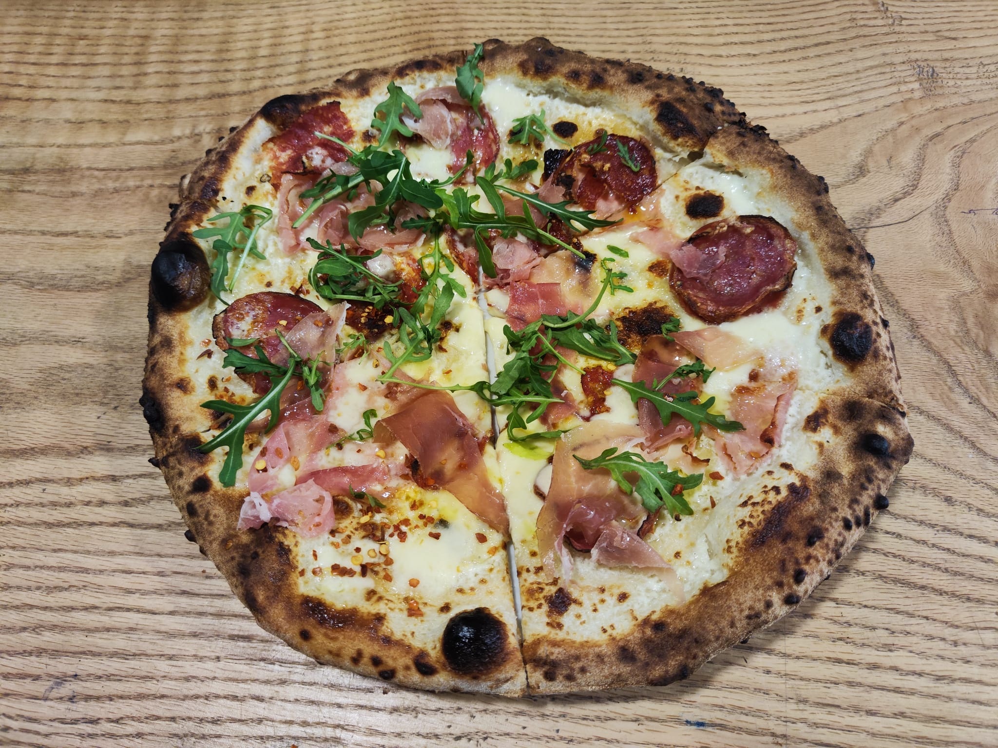 Pizza z salami i prosciutto na desce